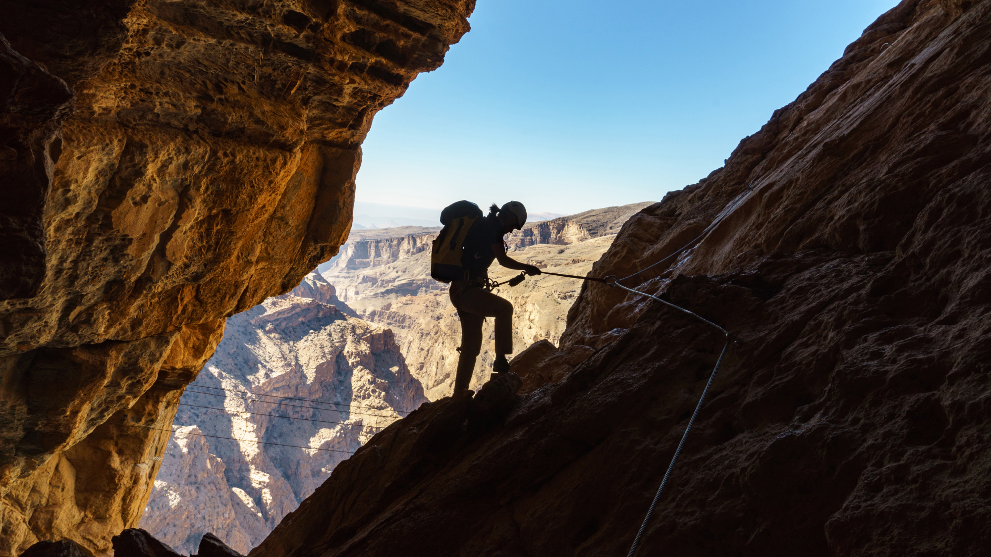 Person climbing mountain to the entrance of a cave in Jabal Akhdar