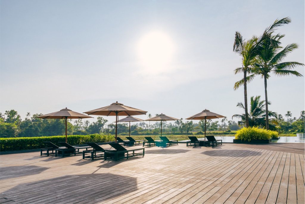 poolside deck with lawn chairs and palm trees