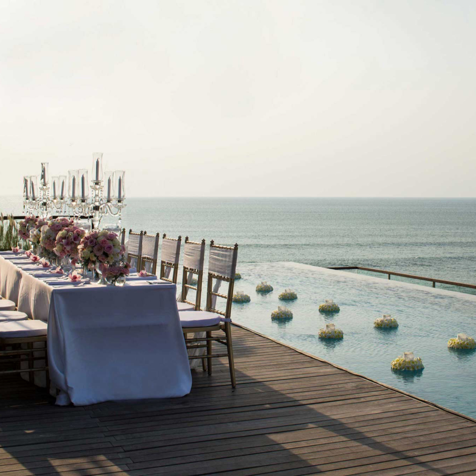 Long table set with silverware and flowers with a sea view