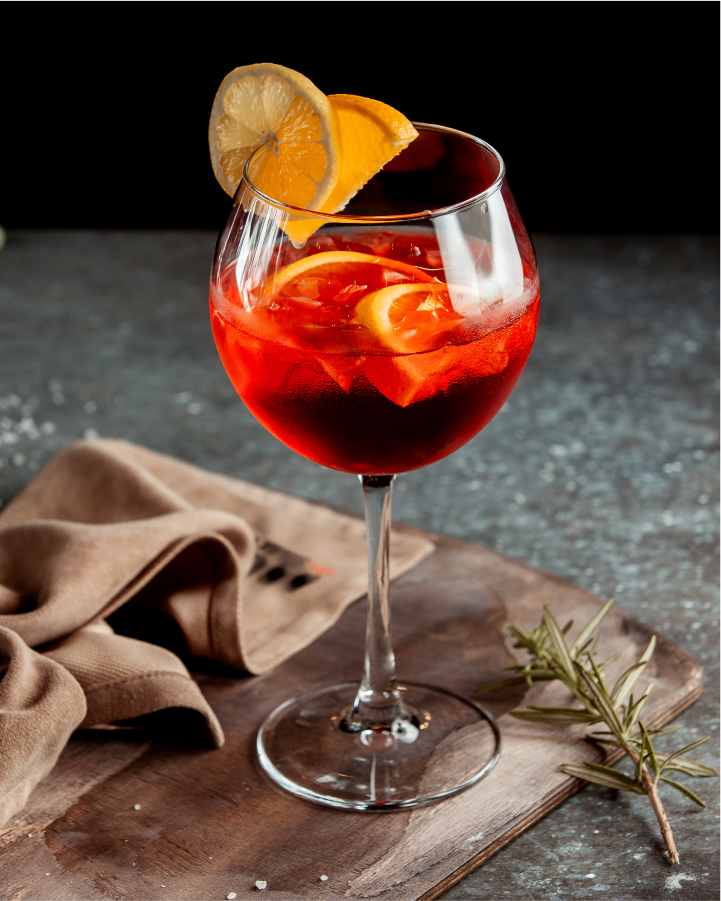Red cocktail with lemon and orange garnish