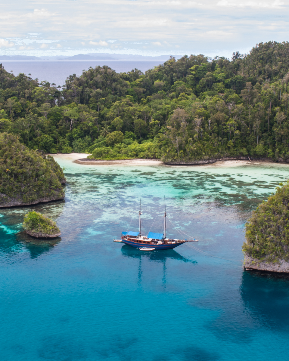 Alila Purnama sailboat anchored near island with lush landscape