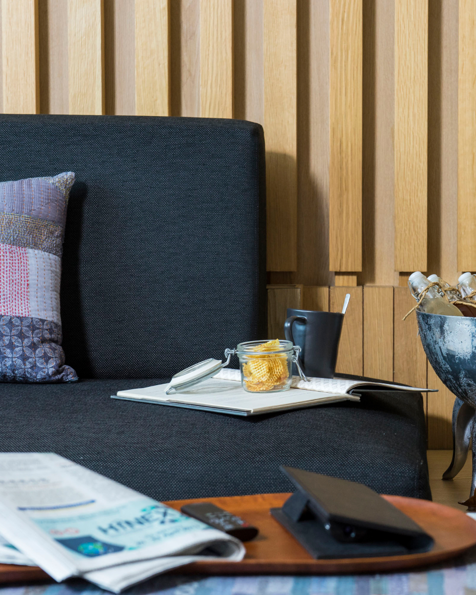 close up of hotel couch with bowl of chips, laptop and newspaper