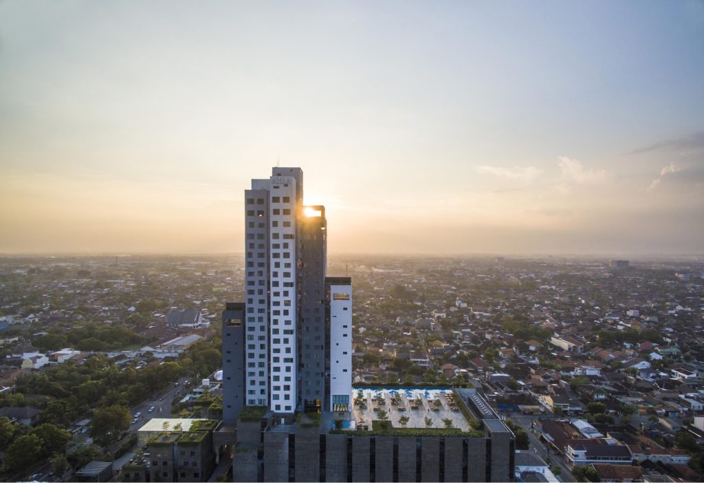 Skyline view of the hotel tower with sun peeking out from behind the building.