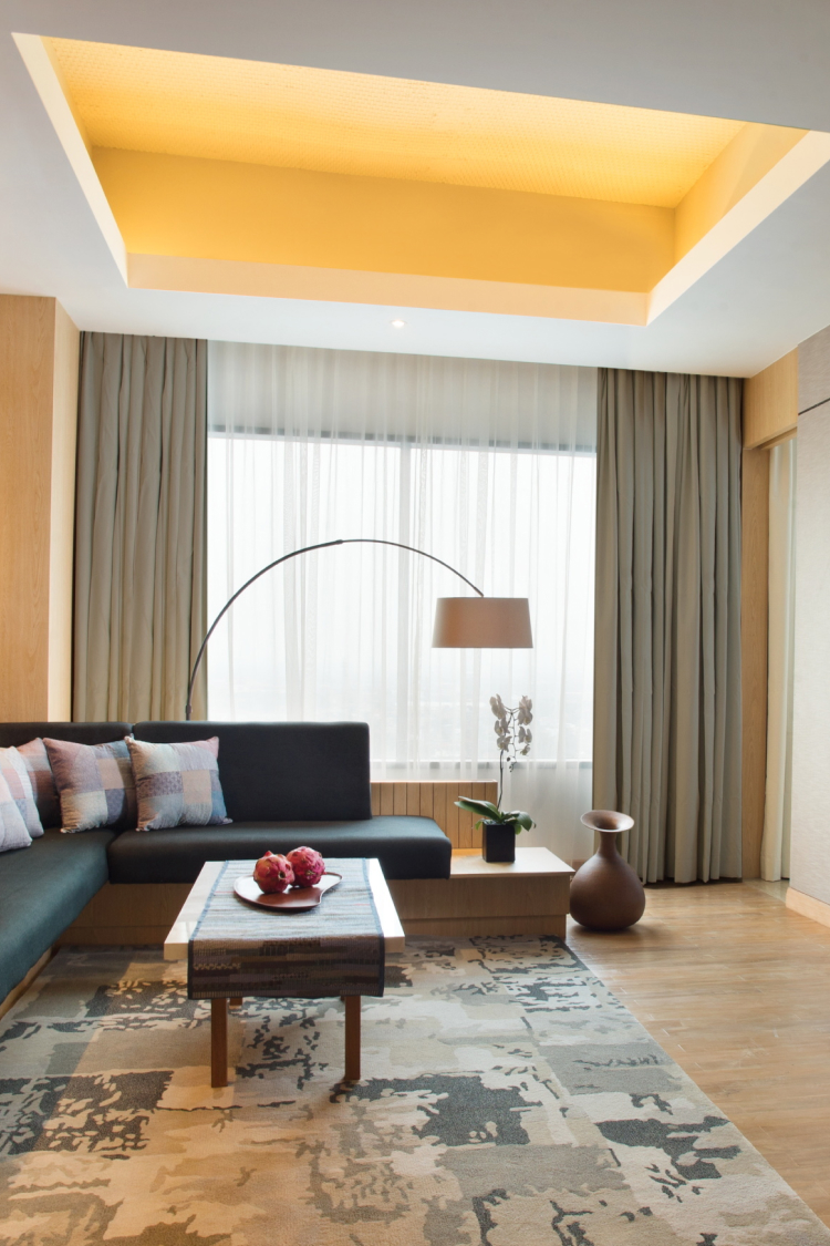 hotel room with green couch, coffee table and overhead lamp